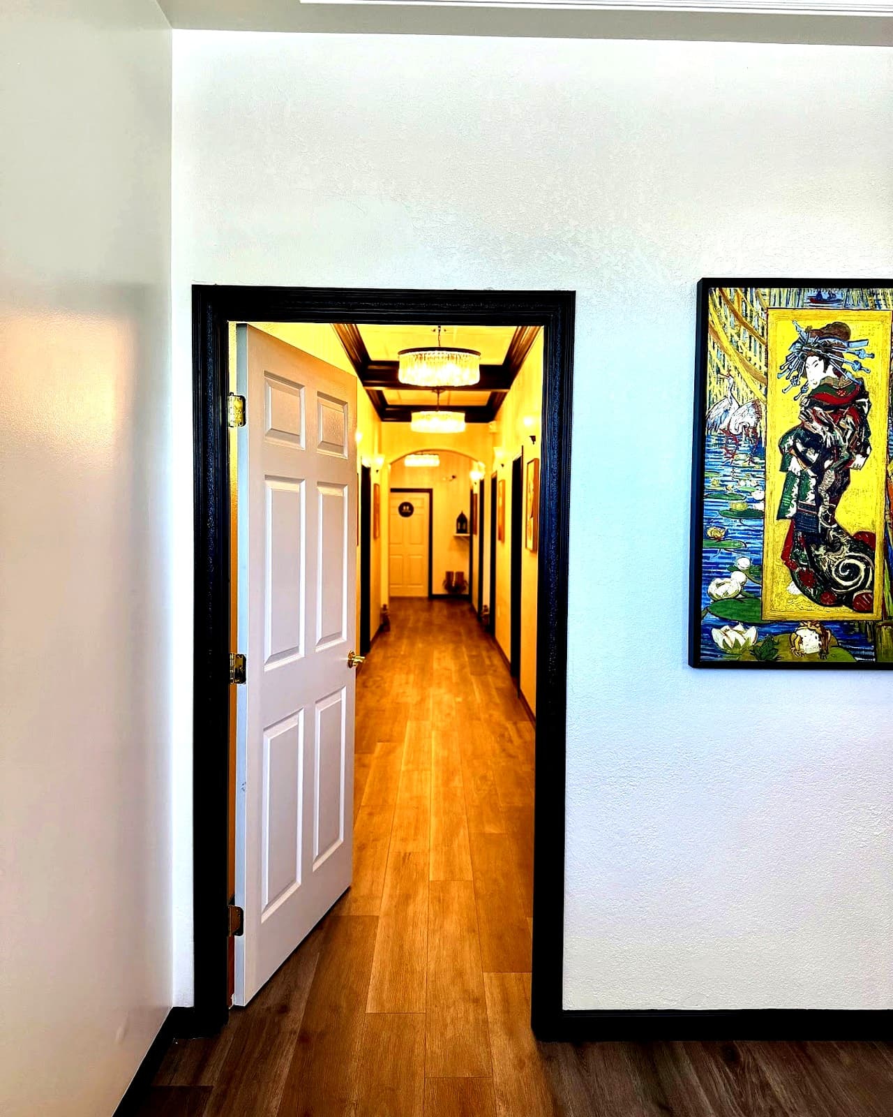 Studio hallway with framed art and warm chandelier lighting